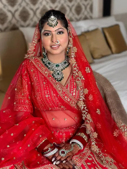 The complete bridal ensemble with the dupatta set. The makeup remains the focal point, enhancing her features while complementing the vibrant red.