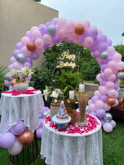 A close-up of the cake tables at the pastel-themed birthday party, decorated with rose petals.