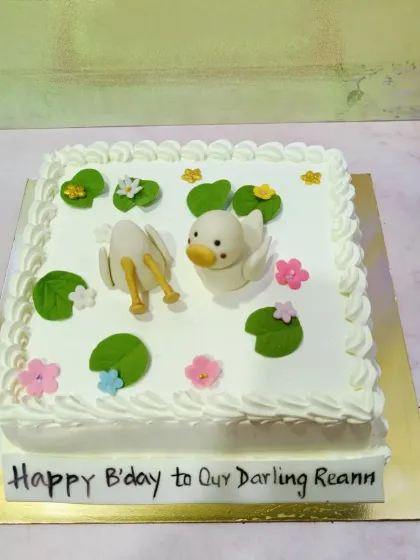 A cute and funny duck-themed cake. This square cake features two fondant ducks, one diving headfirst into the "water."