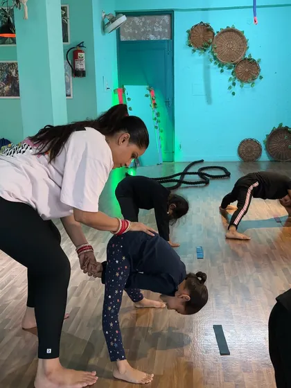 This student is learning a standing forward bend. My guidance on her back helps her understand how to hinge from the hips and maintain a long spine, which is essential for both flexibility and dance technique.