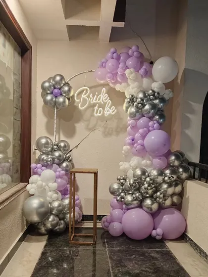A chic "Bride to be" decoration for a balcony or small space, using purple, silver, and white balloons with a neon sign.