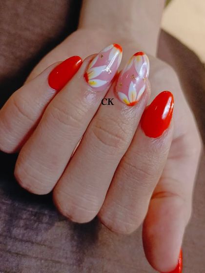 A vibrant orange set with hand-painted white and yellow flower accent nails.