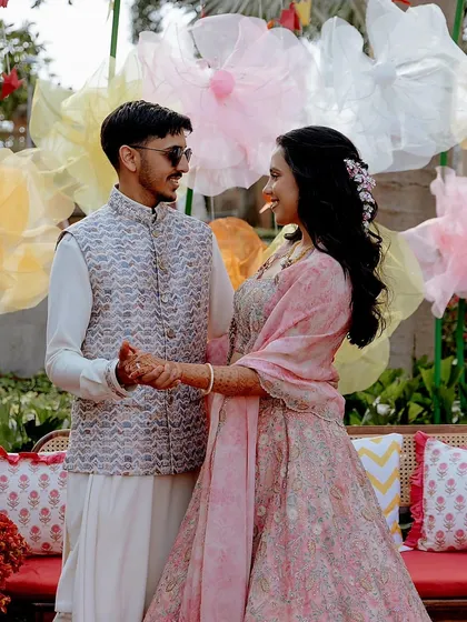 The couple shares a dance in front of the whimsical paper flower backdrop, a perfect candid moment from their Mehendi celebration.