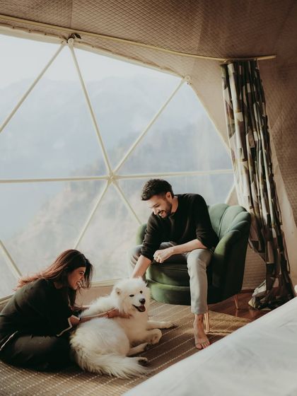 A cozy indoor moment with a couple and their fluffy Samoyed dog in a beautiful geodesic dome in the mountains.