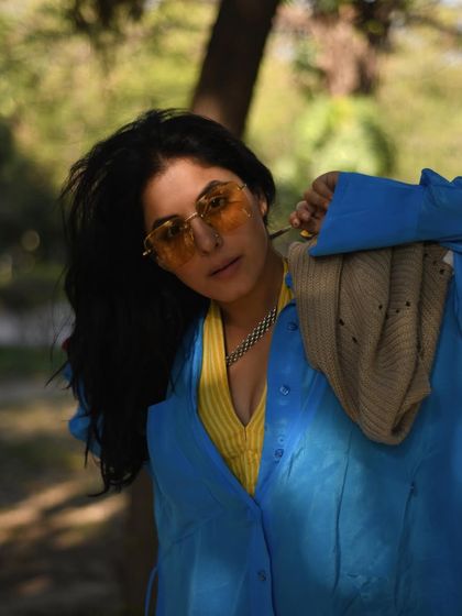 Isha Talwar in a vibrant blue shirt, looking over her shoulder. The colors and the soft, natural background make this a beautiful and engaging portrait.