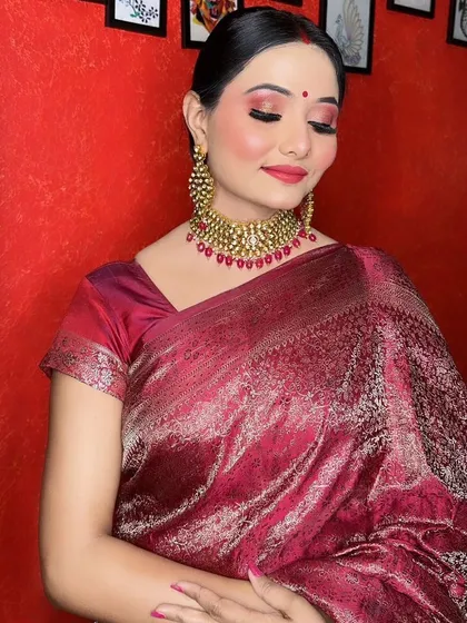 An elegant reception look perfect for evening events. This makeup features glowing skin, rosy cheeks, and a stunning red-toned eyeshadow blended for a soft glam effect, paired with a classic red lip and traditional jewelry.