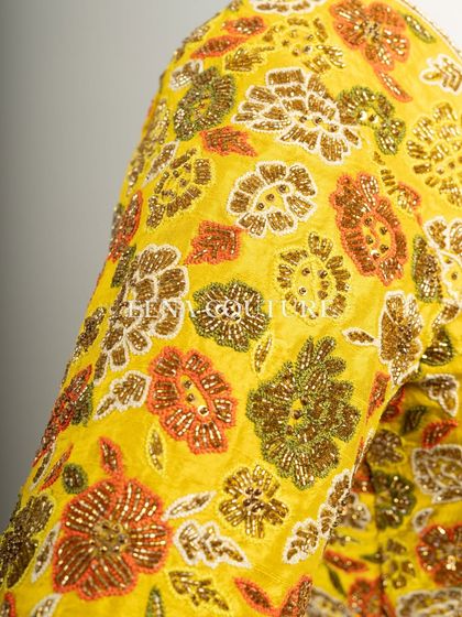 Another take on the yellow raw silk blouse, this piece features a classic Katori cut. The front is kept simple to highlight the fit, while the back and sleeves are adorned with a vibrant floral pattern in multi-colored beadwork.