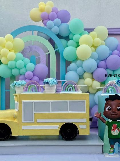 Another view of the Cocomelon bus and character cutouts, framed by beautiful pastel balloon garlands.
