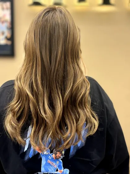 This back view showcases perfectly placed highlights that add texture and a healthy glow. The soft waves help the different tones catch the light beautifully, creating a dimensional look.