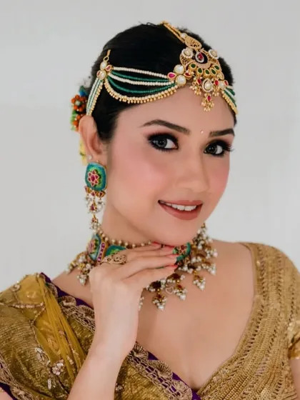 A close-up of the client's traditional look. The hair is styled in a classic bun, providing a perfect base for the multi-layered matha patti.