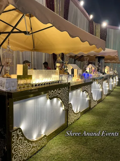 An elegant, illuminated catering counter set up on the lawn, with awnings to provide a food-stall-like experience.