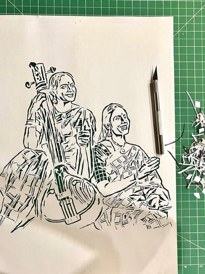 The full portrait of Ranjani and Gayatri on my cutting mat. This was a complex piece that involved capturing not just their likenesses but also the details of their saris and the instrument.