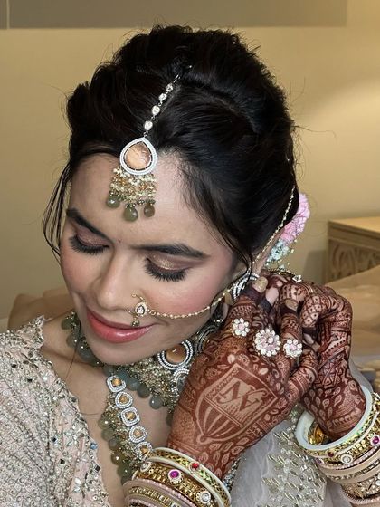 A beautiful bride getting ready, her hair styled in a textured updo with pink carnations.
