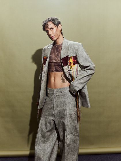 The final look for this model, featuring a tailored suit with deconstructed patch details and a sheer top.