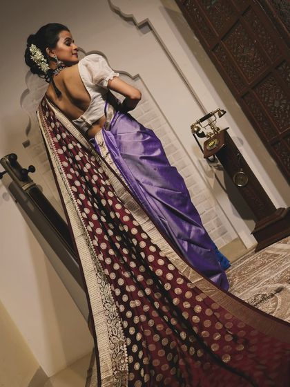 A vintage-inspired photoshoot look. The dramatic trail of the saree and the classic backless blouse are complemented by a traditional braided hairstyle.