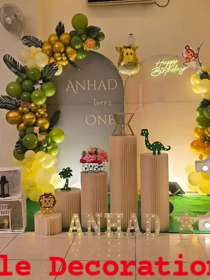 This wide-angle view showcases a grand jungle theme birthday party. The setup includes a custom backdrop, marquee number 'ONE', life-sized animal props like a lion and tiger, and organic balloon garlands to create an immersive safari experience.