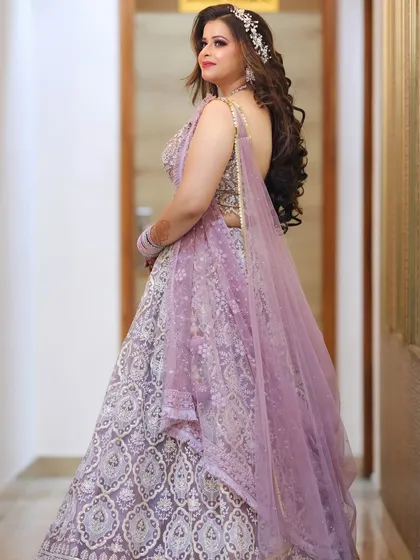 The backless blouse and flowing dupatta are perfectly complemented by voluminous curls and a radiant makeup look.
