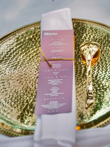 Another example of my personalized table settings. A custom menu is placed on a hammered gold plate with an ornate golden spoon, showing how I tailor every detail to the client's vision.