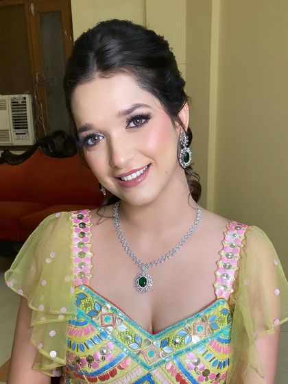 Stunner alert! This mehndi look is so fun and vibrant. We used a soft pink eyeshadow and added a few rhinestones for that extra sparkle, matching her colorful outfit.