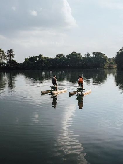 Two people on water cycles, seen from a distance, enjoying the tranquility of the lake at their own pace.
