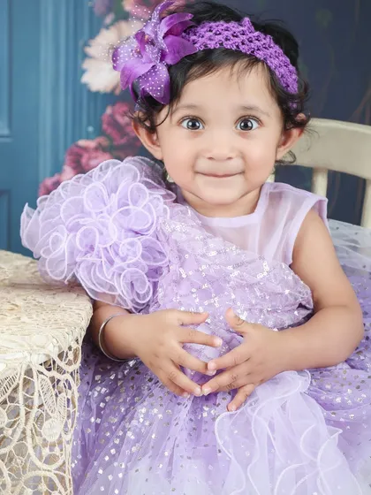 A sweet portrait of a baby girl in a beautiful lavender dress, ready for a royal ball or a garden party.