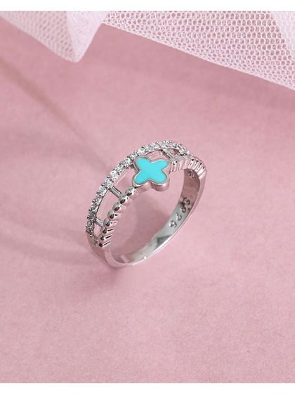 A delicate silver ring with a turquoise-colored clover charm on an openwork, diamond-studded band. This is a beautiful piece that tells a story of sparkle and luck.