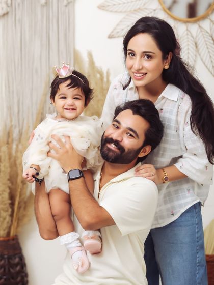 A bright and happy studio family portrait. The parents and their adorable daughter smile for the camera, creating a timeless memory of this stage in their lives.