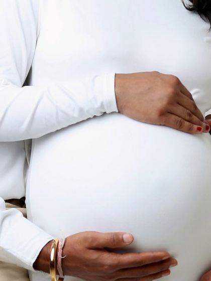 A close-up shot focusing on the hands cradling the bump. This detailed photo symbolizes the love, protection, and connection of the family-to-be.