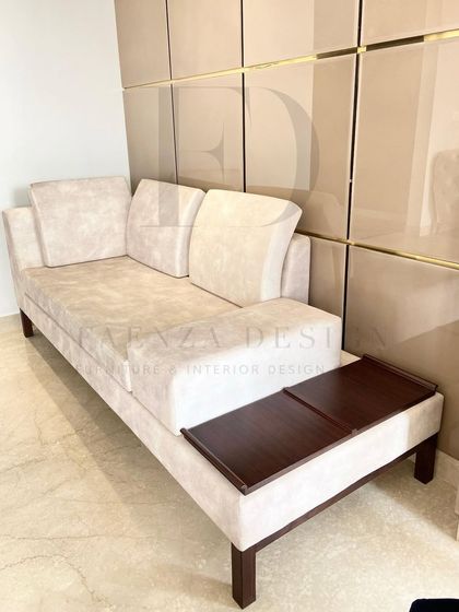 A custom daybed designed for a living room corner. This versatile piece features a built-in wooden side table, making it a perfect spot for lounging, reading, or hosting an extra guest.