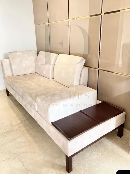 A custom daybed designed for a living room corner. This versatile piece features a built-in wooden side table, making it a perfect spot for lounging, reading, or hosting an extra guest.