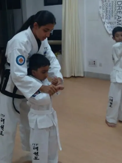 A female instructor provides hands-on correction to a young student, ensuring proper form from the very beginning.