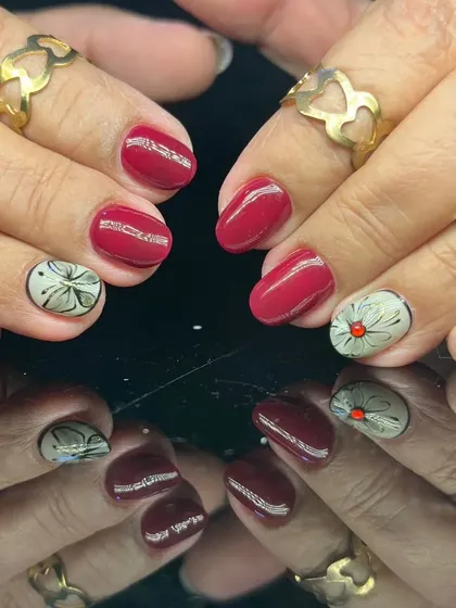 A sophisticated red manicure with accent nails featuring a unique grey and white floral design.
