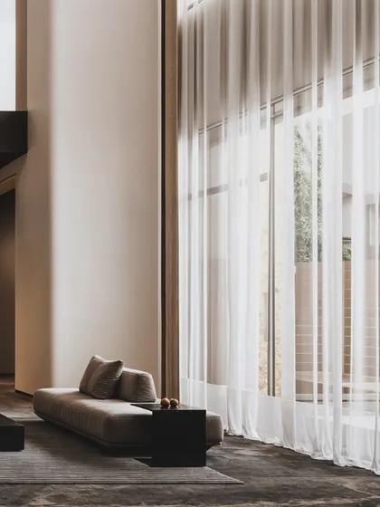 This shot captures the soft, diffused light filtering through sheer curtains in a minimalist living area, creating a sense of calm and tranquility.