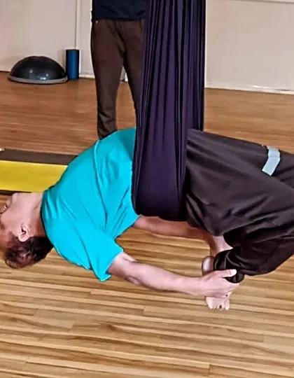 A deep backbend pose performed with the support of the aerial silk. The hammock cradles the back, allowing the student to relax into the stretch and increase spinal flexibility.