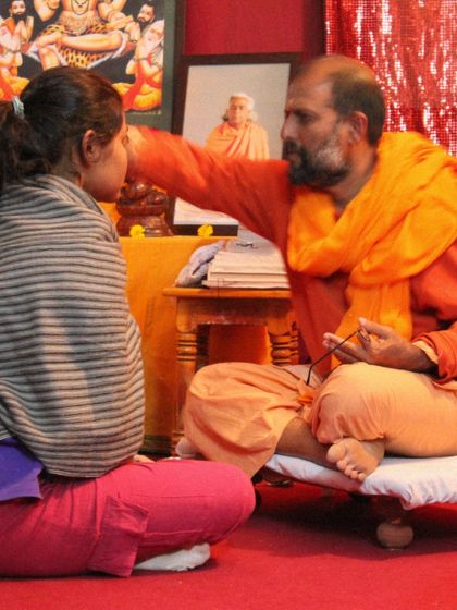 A powerful moment from a 2011 initiation ceremony, where a Swami bestows a blessing upon a new student, marking the beginning of her transformative journey.