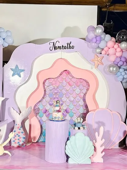 A wide shot of Namratha's mermaid theme birthday, showing how all the elements come together. The setup includes a layered backdrop, a ship prop, and plenty of under-the-sea details.
