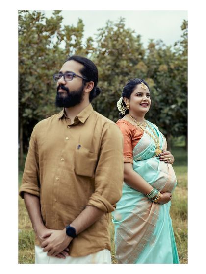 A candid shot of an expecting couple looking towards the future, standing together in a natural outdoor setting during their Seemantham celebration.