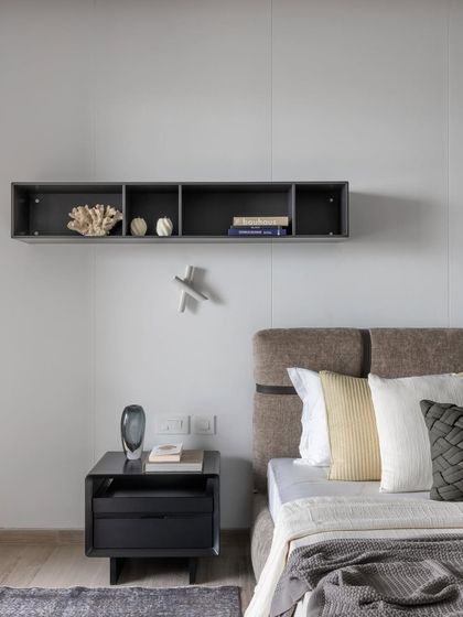 Serenity captured within four walls. This minimalist bedroom uses a calm, neutral palette and clean lines to create a peaceful retreat. The floating shelf provides a space for curated objects without adding clutter.