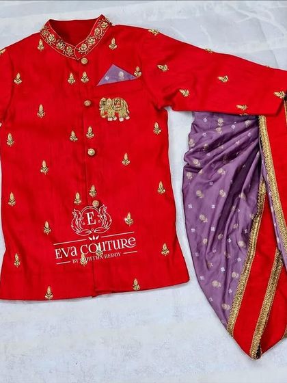 A bright red sherwani-style kurta with elephant embroidery on the pocket. It's paired with a purple dhoti with butti prints.