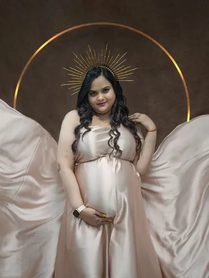 Another look at the champagne satin gown. Here, we've draped the fabric around the mom-to-be to create a soft, angelic look, complemented by the halo prop.