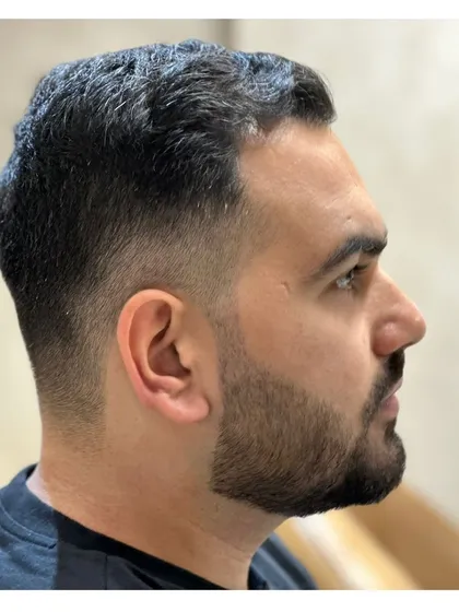 A close-up profile of a fresh fade and beard lineup. The precision in the lines around the ear and beard is key to this clean style.