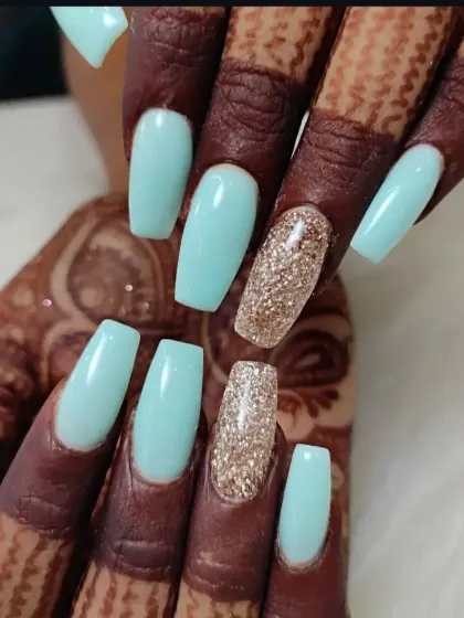 A chic combination of pastel blue-green nails with a sparkling gold glitter accent nail on a coffin shape.