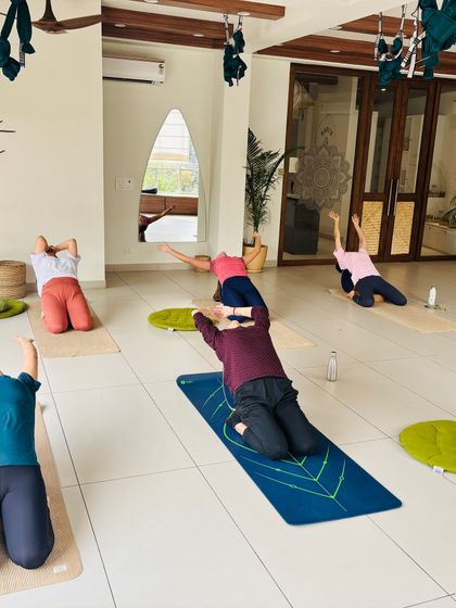 A class moves through a heart-opening backbend on their knees, stretching the front of the body.