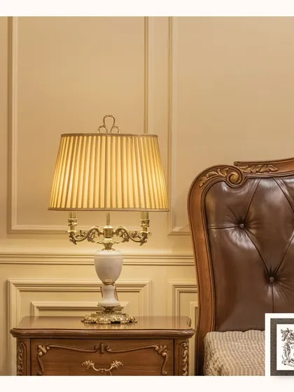 This classic table lamp brings a refined touch to a bedside table. The combination of a white marble-finish base, ornate brass details, and a pleated shade provides warm, ambient lighting, perfect for creating a tranquil and luxurious bedroom retreat.