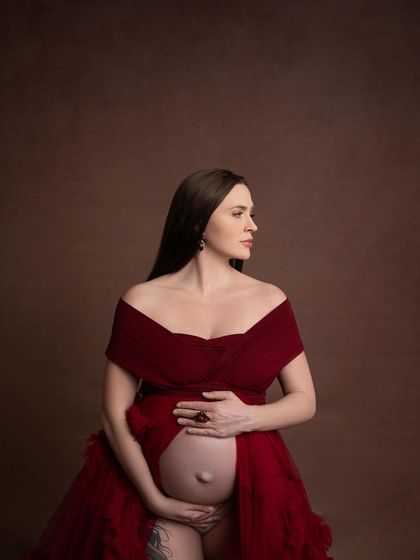 This intimate angle focuses on the connection between mother and baby, with her hands gently cradling her bump. The artistry of her tattoo is beautifully featured.