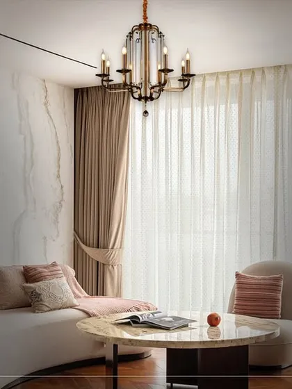 A traditional candelabra-style chandelier brings a classic, refined touch to this elegant living room. The fixture provides a warm, central light source that enhances the room's soft, neutral palette.
