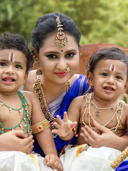 A beautiful family portrait with a mother and her two little boys dressed as Krishna, their smiles lighting up the frame.