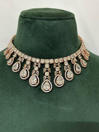 A rose-gold plated American diamond choker with teardrop pendants. This rental piece is perfect for a modern and chic look.