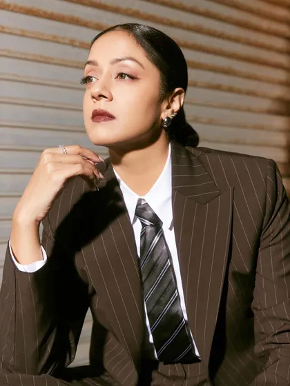 A close-up of Jyotika in a brown pinstripe suit, featuring a bold lip and a sleek hairstyle that completes this powerful androgynous look.