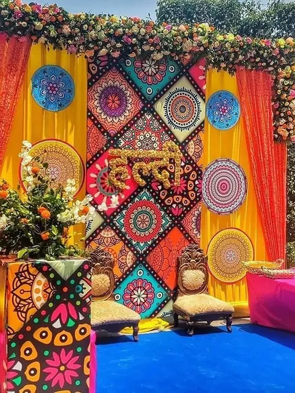 This is not your average Haldi decor. For this event, we designed a vibrant, Rajasthani-inspired backdrop using colorful printed panels, mandala art, and the word "Haldi" crafted from fresh marigold flowers. It’s a perfect example of how we mix traditional elements with modern design.